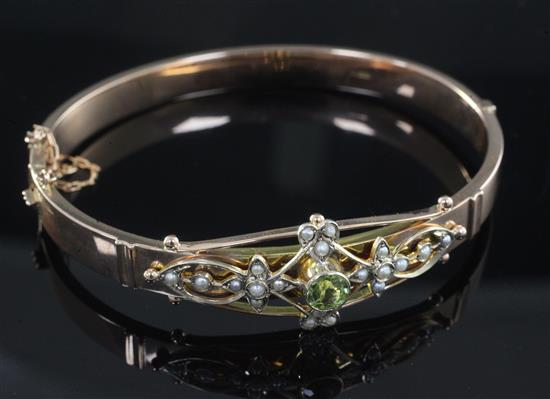 A George V 9ct gold, peridot and seed pearl set hinged bangle.